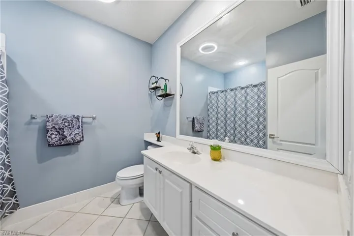 Bathroom featuring a white vanity with integrated sink, a large wall-mounted mirror, and tile flooring