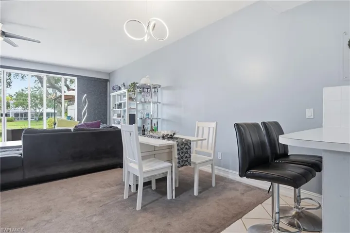 Open-concept living space featuring a modern chandelier, ceiling fan, large sliding glass doors, and a kitchen pass-through with a white countertop