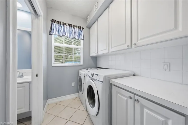 Functional laundry area featuring white shaker-style cabinetry, a white countertop, and white square tile backsplash