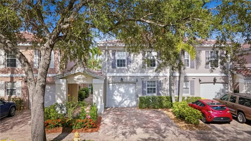 Two-story townhome featuring a tiled roof, stucco exterior, and front-facing garage