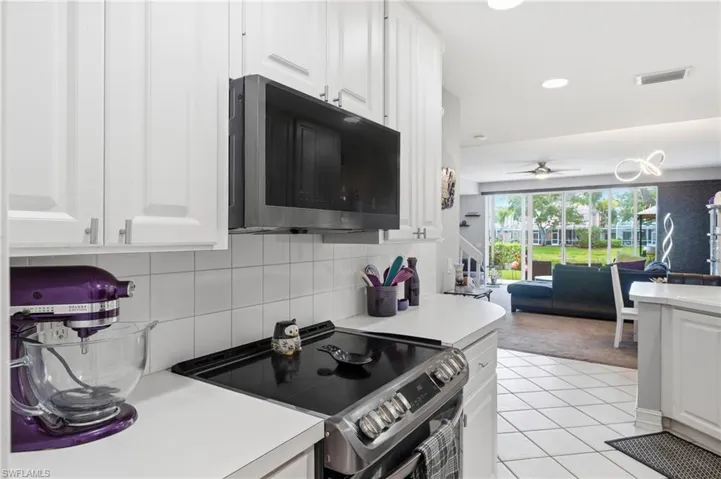 Kitchen with white cabinetry, a built-in microwave, and a smooth-top range