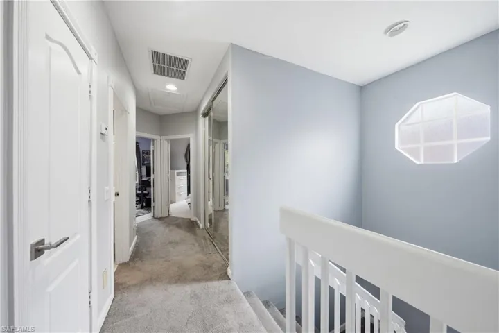 Carpeted hallway featuring white paneled doors with brushed nickel hardware, recessed lighting, and a mirrored closet