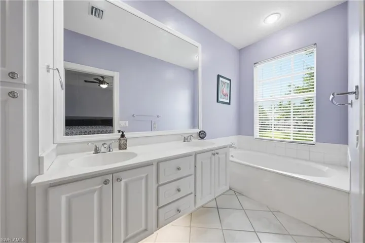 Bathroom featuring a dual vanity with white cabinetry, integrated sinks, and a large mirror
