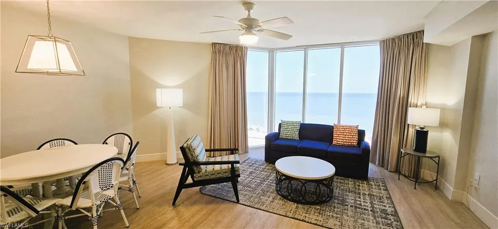 Living room featuring a wall of windows, a water view, light hardwood / wood-style flooring, and ceiling fan