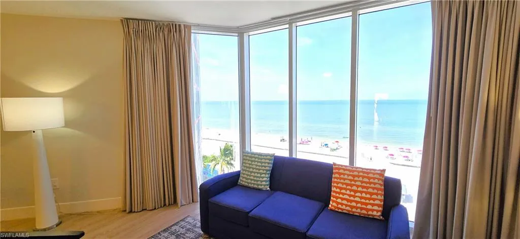 Sitting room with a beach view, a water view, light wood-type flooring, and floor to ceiling windows