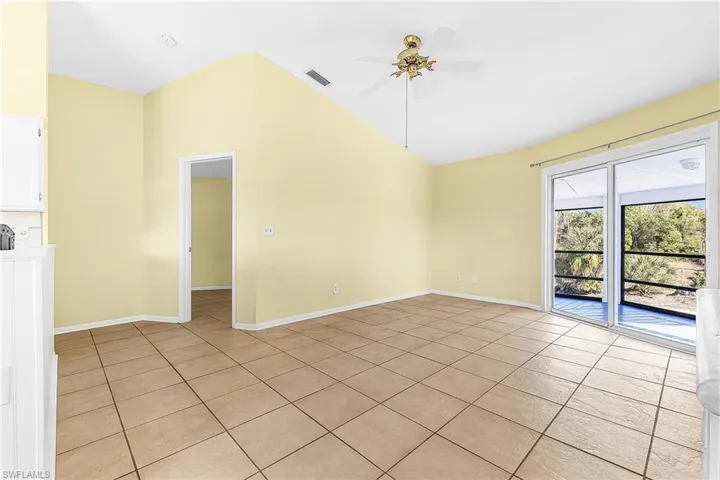 Spare room with ceiling fan, vaulted ceiling, and light tile patterned floors