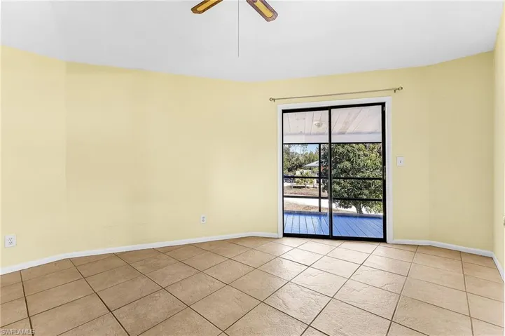 Tiled spare room featuring a ceiling fan and baseboards