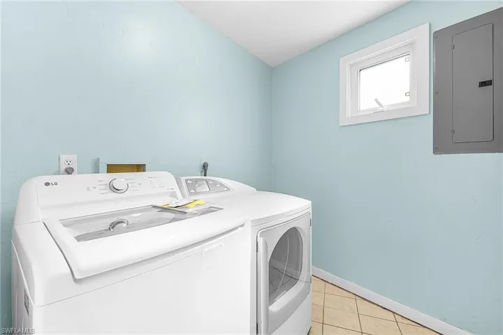 Laundry area located on main living floor, featuring electric panel, washer and clothes dryer, and light tile patterned floors