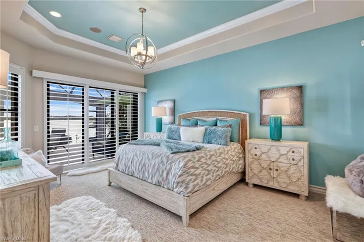 Bedroom with a tray ceiling, crown molding, carpet flooring, and an inviting chandelier