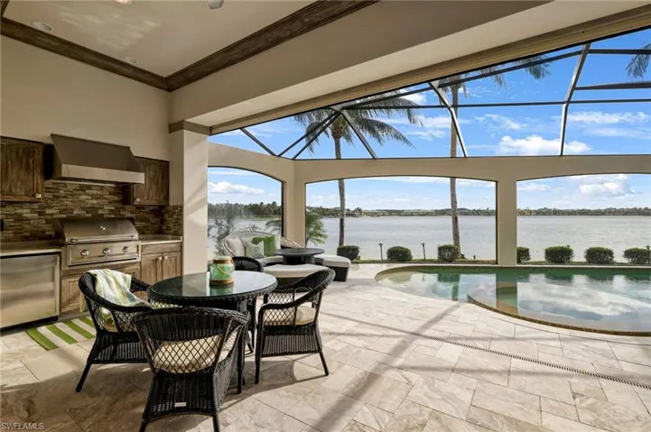 View of patio with a lanai, area for grilling, a grill, and a water view