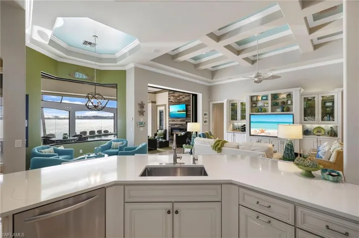 Kitchen with dishwasher, coffered ceiling, white cabinets, sink, and a fireplace