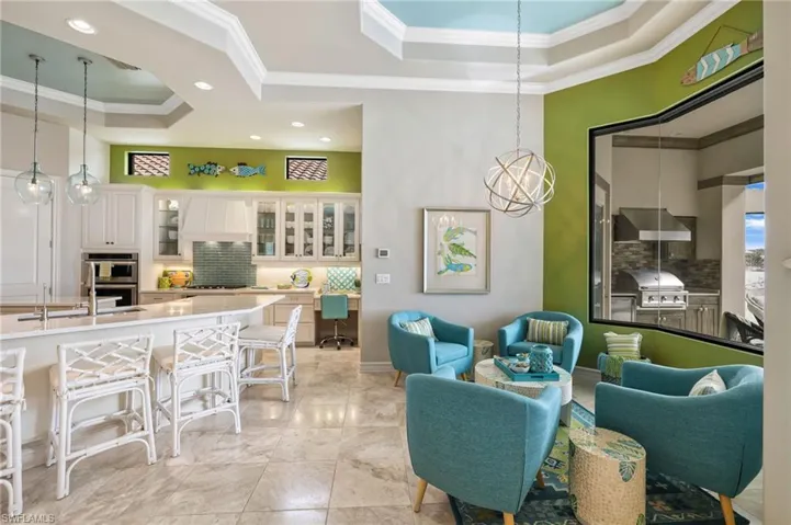 Living room with a raised ceiling, ornamental molding, and sink