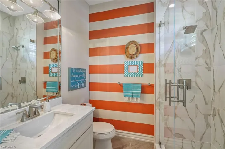 Bathroom featuring tile patterned floors, vanity, toilet, and a shower with shower door