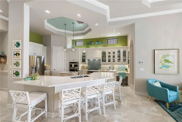 Kitchen featuring a kitchen breakfast bar, backsplash, stainless steel appliances, sink, and hanging light fixtures