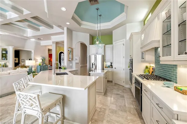 Kitchen featuring backsplash, a large island with sink, sink, appliances with stainless steel finishes, and a breakfast bar area