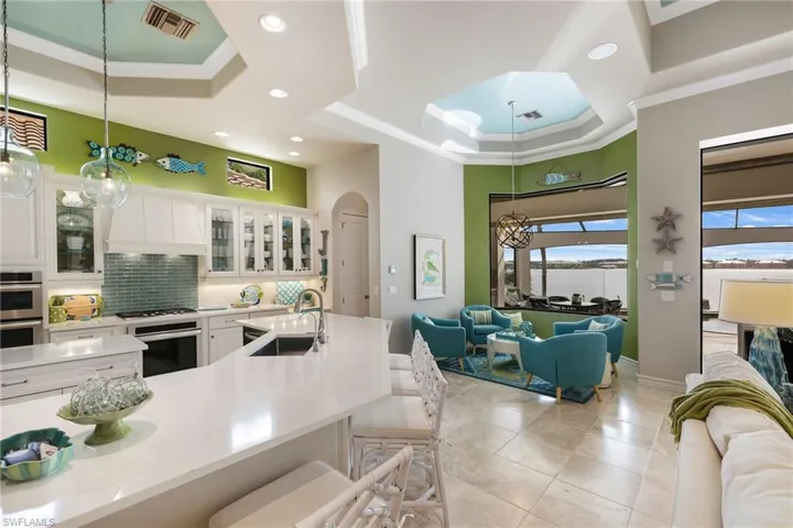 Kitchen with pendant lighting, white cabinets, sink, tasteful backsplash, and a kitchen bar