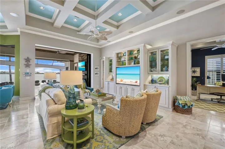 Living room featuring beamed ceiling, crown molding, ceiling fan, and coffered ceiling