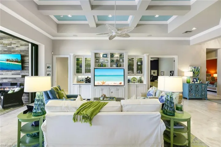 Living room with beam ceiling, crown molding, ceiling fan, and coffered ceiling