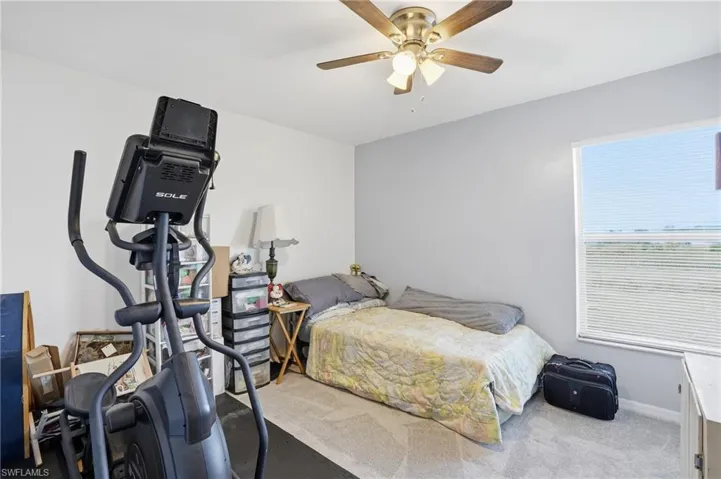 Carpeted bedroom with ceiling fan and baseboards