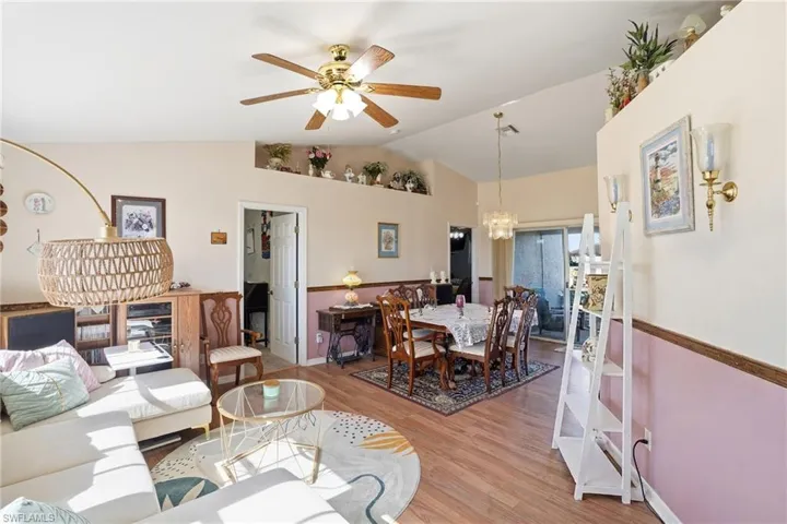 Living room with ceiling fan, light wood finished floors, and hanging lights