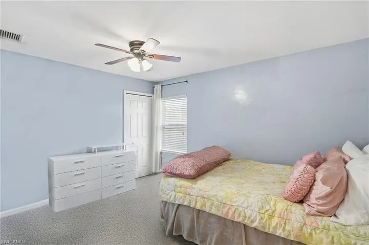 Carpeted bedroom with a closet and a ceiling fan