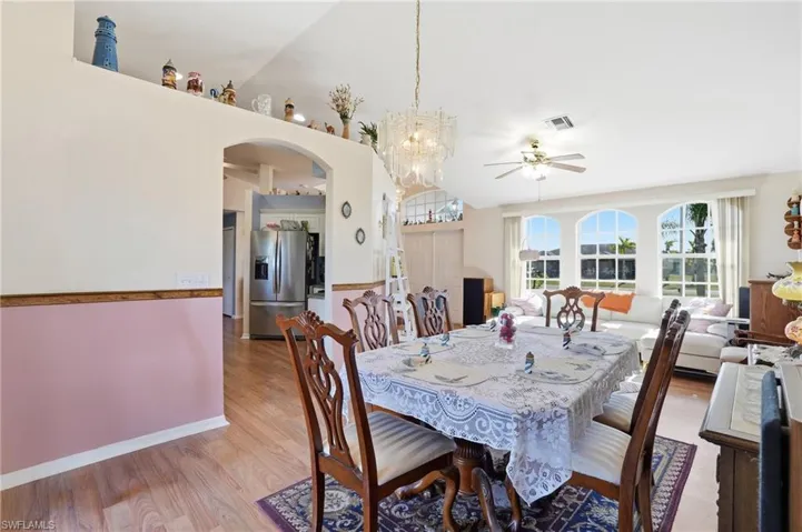 Dining area with light wood finished floors, a chandelier, a ceiling fan, and arched walkways
