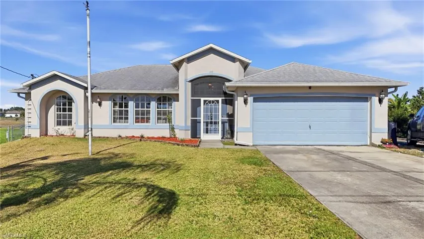 Ranch-style home with stucco siding, concrete driveway, an attached garage, roof with shingles, and a front yard