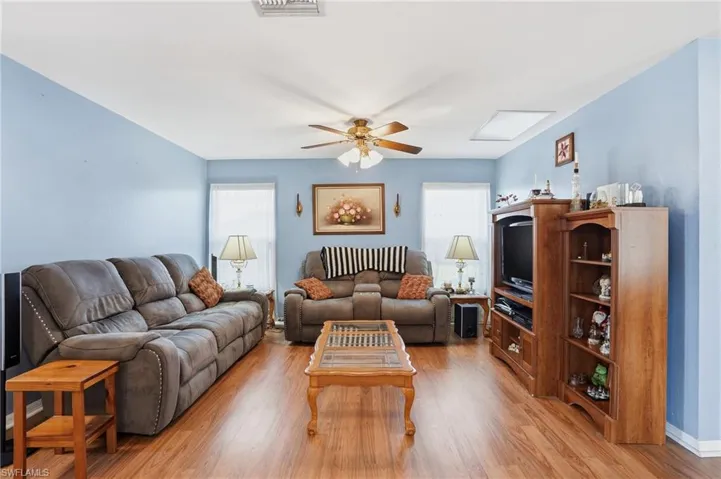 Living area with plenty of natural light, light wood-style flooring, and ceiling fan