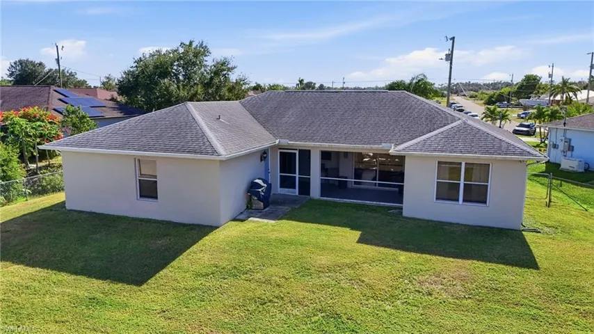 Rear view of house with stucco siding and roof with shingles