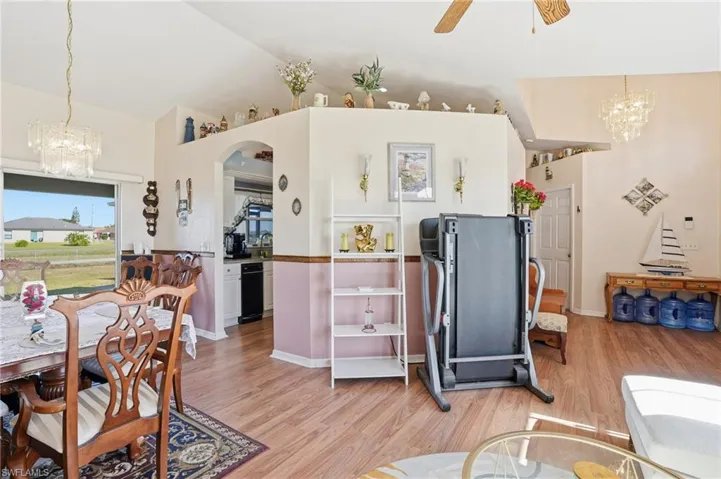 Dining space with hanging lights, a ceiling fan, light wood-style floors, arched walkways, and lofted ceiling