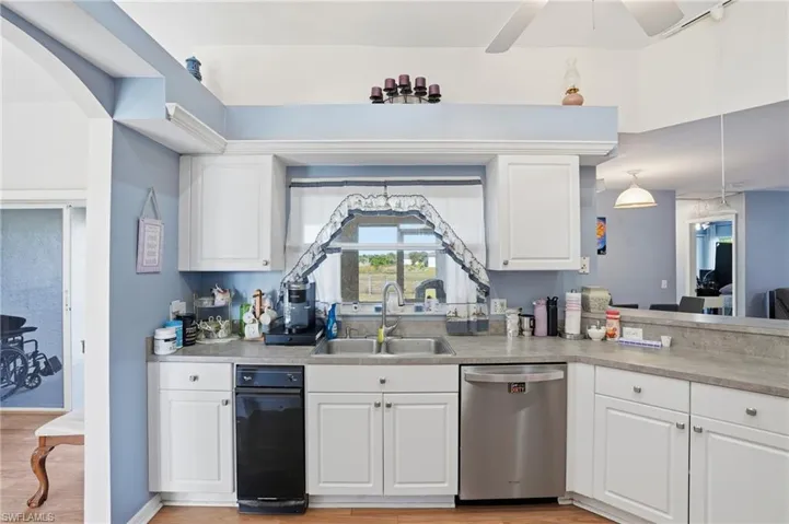 Kitchen featuring white cabinetry, stainless steel dishwasher, and light countertops