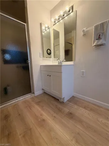 Bathroom featuring a shower stall, vanity, and light wood-style floors