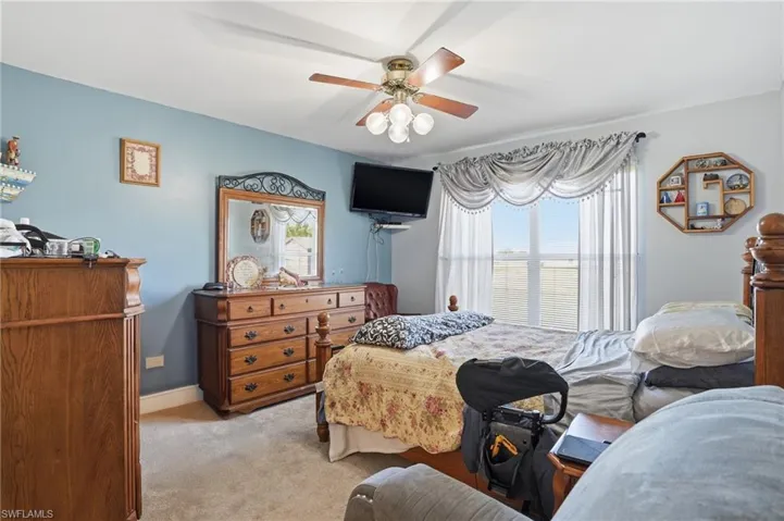 Bedroom with light carpet, multiple windows, and ceiling fan