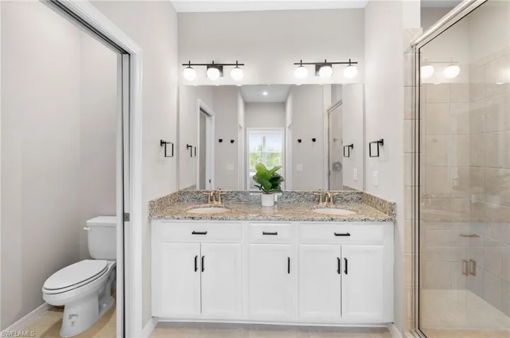 Full bath with double vanity, a stall shower, and light tile patterned floors