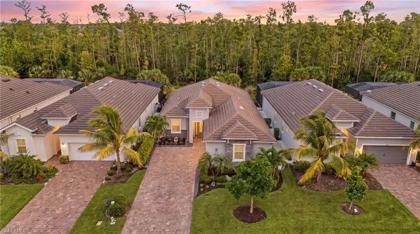 Contemporary architecture featuring a tile roof, paver driveway, and a landscaped front yard with palm trees