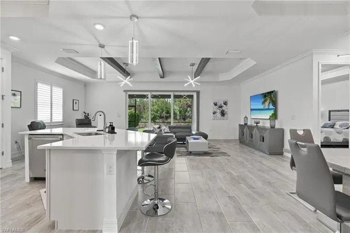 Open-concept living space with wood-finish flooring, a kitchen island with stone countertop, recessed lighting, and sliding glass doors