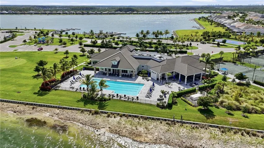 Expansive waterfront property featuring a large swimming pool, multiple tennis courts, and a marina with boat slips