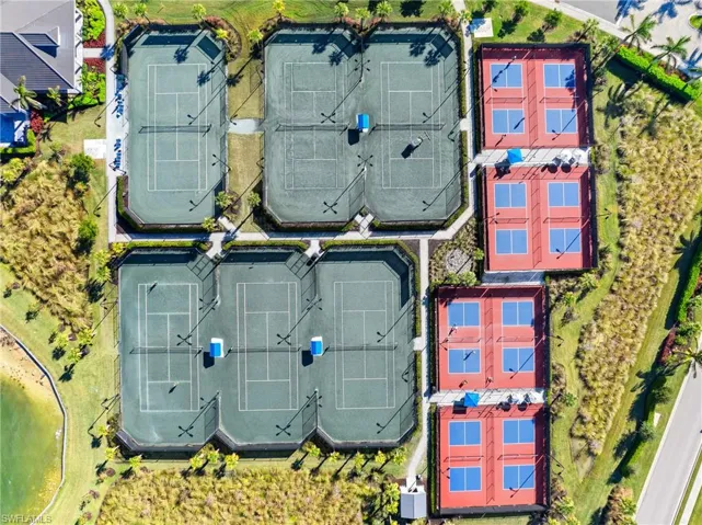 Multiple hard tennis courts with perimeter fencing, multiple hard pickleball courts, and a surrounding landscape of green spaces and natural vegetation