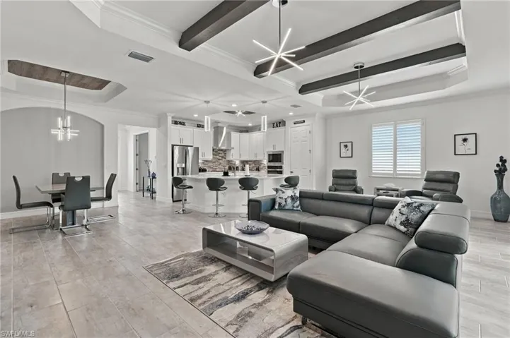 Open-concept living space with wood-finish tile flooring, a coffered ceiling with exposed beams, and contemporary pendant lighting