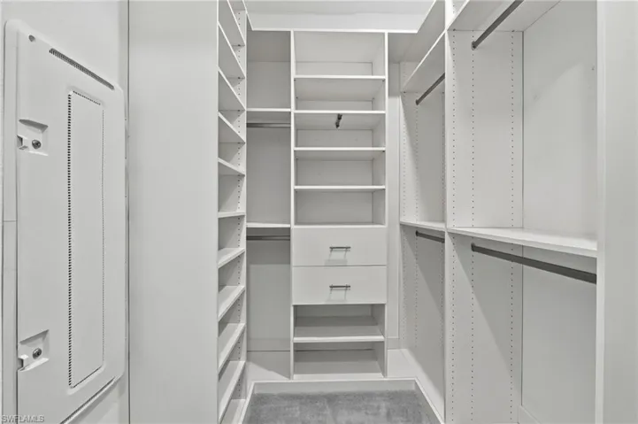 Custom closet system featuring multiple shelving units, hanging rods, and integrated drawers with contemporary hardware
