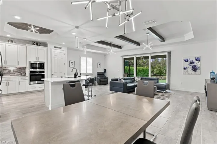 Open-concept living space featuring a modern kitchen, built-in stainless steel appliances, a center island with sink, and tile flooring throughout