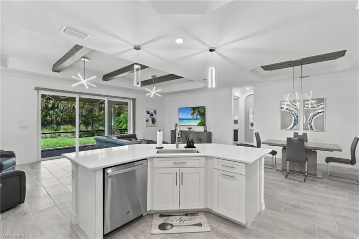 Open-concept living space featuring a kitchen island with white cabinetry, stainless steel dishwasher, and a white countertop