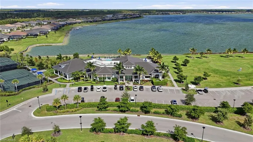 Clubhouse with a swimming pool, tennis courts, and a large parking area