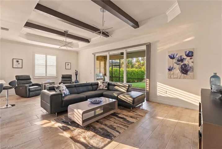 Tray ceiling with dark wood-finish beams, tile flooring, and sliding glass doors