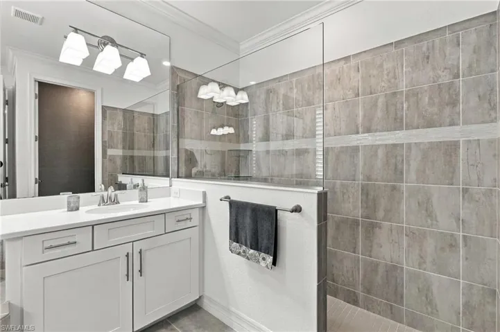 White vanity with an integrated sink and brushed nickel faucet, large mirror, and three-light vanity fixture