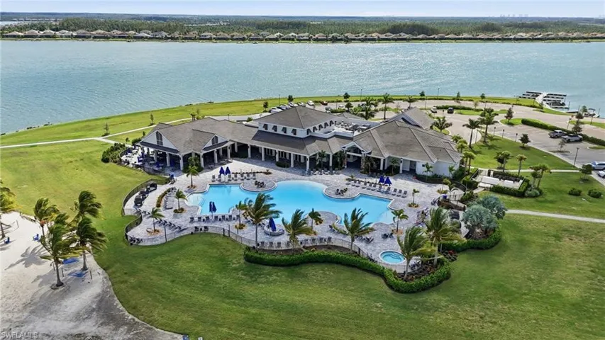 Expansive waterfront clubhouse featuring a resort-style swimming pool, spa, and mature landscaping