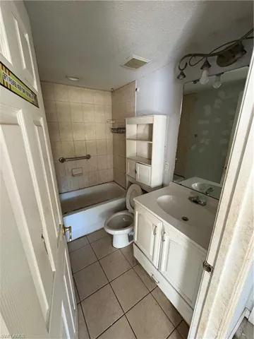 Bathroom with tile patterned floors, vanity, a textured ceiling, and washtub / shower combination