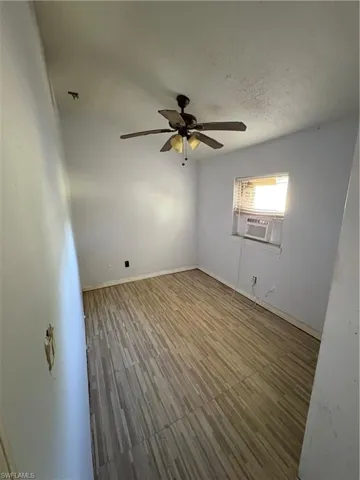 Empty room featuring a textured ceiling, a ceiling fan, and wood finished floors