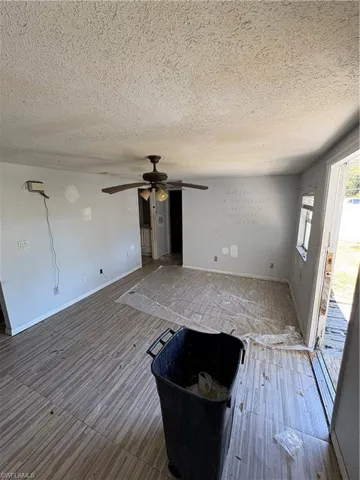 Unfurnished living room featuring a ceiling fan, a textured ceiling, and wood finished floors