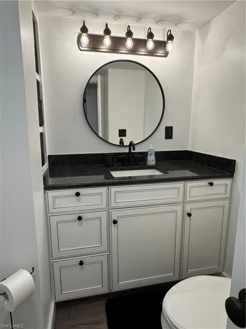Half bathroom with vanity and dark wood-style flooring
